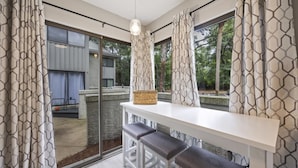 A modern kitchen with a white countertop, three bar stools, and a hanging light fixture. - Harbour Master - Monthly Rates Through 2/28/26! 3 Bedroom Villa (Hilton Head Island)