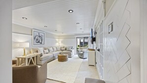 A modern living room with a sofa set, a coffee table, and a TV mounted on the wall. - Harbour Master - Monthly Rates Through 2/28/26! 3 Bedroom Villa (Hilton Head Island)