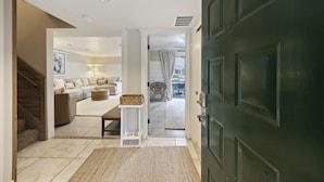 A hallway leading to a living room with a sofa, a small table, and a basket. - Harbour Master - Monthly Rates Through 2/28/26! 3 Bedroom Villa (Hilton Head Island)