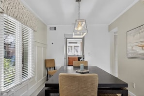 A dining area with a dark wooden table, four chairs, and a hanging light fixture. - Sea Pines - 867 Ketch Court 2 Bedroom Home (Hilton Head Island)