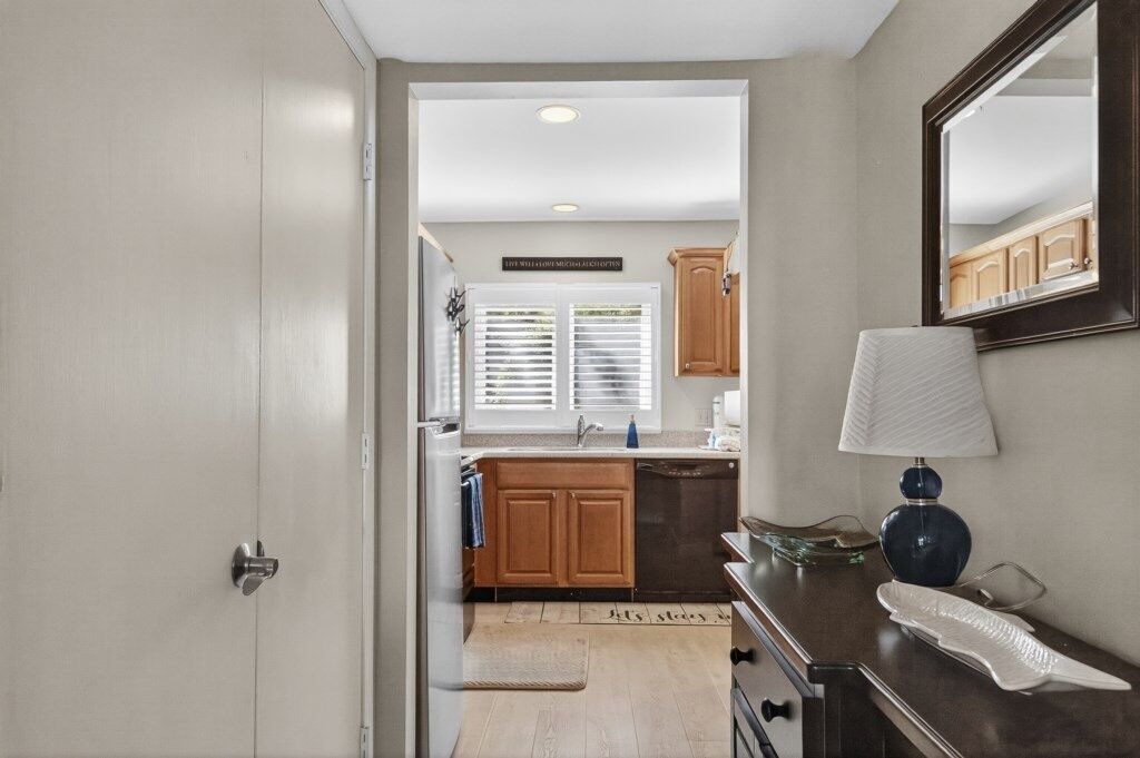 A compact kitchen with wooden cabinets, a sink, and a window with blinds.