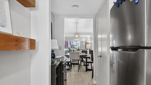A modern kitchen with a stainless steel refrigerator, wooden shelves, and a dining area with a chandelier. - Sea Pines - 867 Ketch Court 2 Bedroom Home (Hilton Head Island)