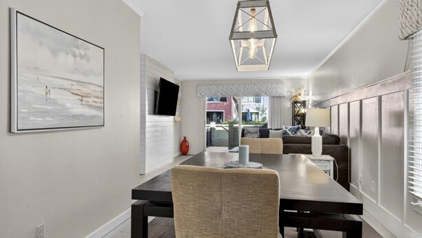 A modern dining area with a long table, cushioned chairs, and a hanging light fixture. - Sea Pines - 867 Ketch Court 2 Bedroom Home (Hilton Head Island)