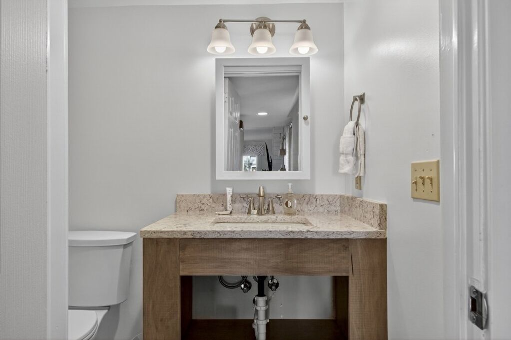 A bathroom with a white toilet, a wooden vanity with a sink, and a mirror above the vanity.
