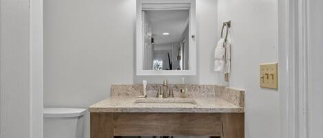 A bathroom with a white toilet, a wooden vanity with a sink, and a mirror above the vanity.