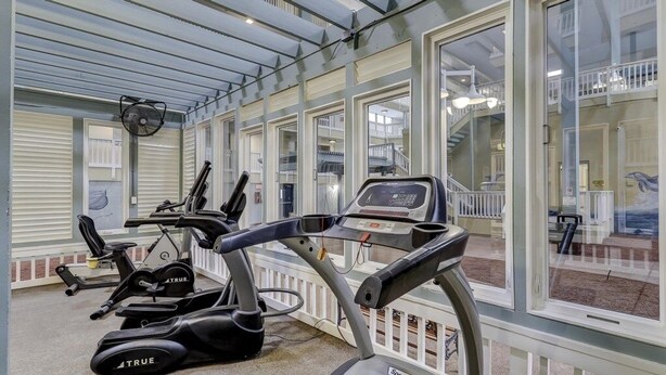 Une salle de sport équipée de matériel d’exercice, dotée de grandes fenêtres et offrant une vue sur l’extérieur.