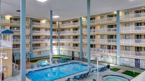 Un hôtel à plusieurs étages doté d’une piscine centrale entourée de chaises longues, de balcons et d’un petit jacuzzi.