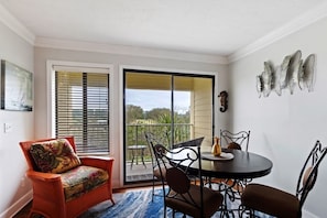 Un coin repas avec une table ronde, des chaises et une vue sur l’extérieur, accessible par une porte-fenêtre coulissante.