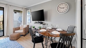 Un comedor con una mesa redonda, sillas y un televisor montado en la pared.