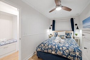 A bedroom with a bed, a ceiling fan, a nightstand, a lamp, and a window with curtains. - Palmetto Breeze - Monthly Rates! 1 Bedroom Condo (Hilton Head Island)