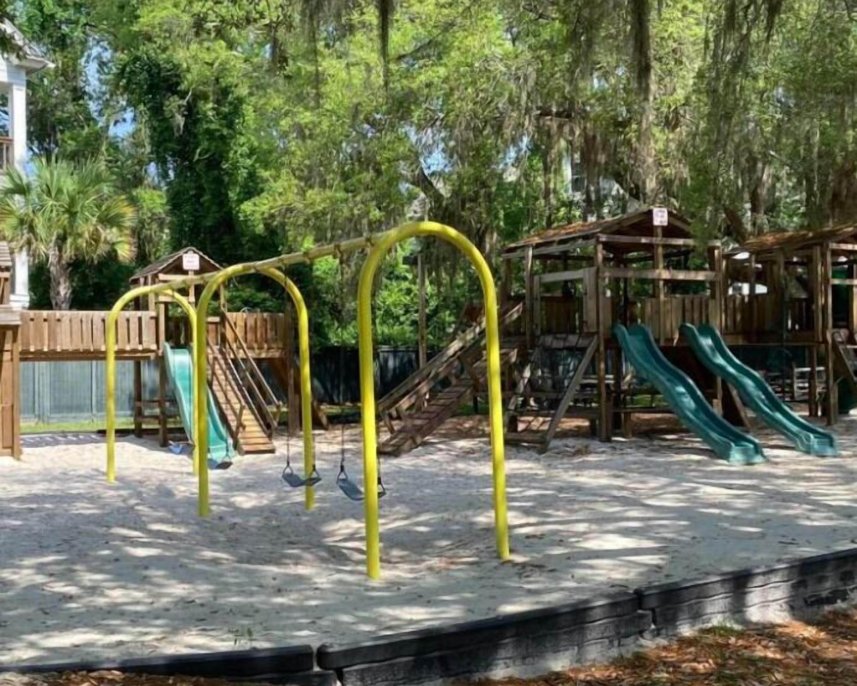 Ein Spielplatz mit gelben Schaukeln, einer Rutsche und einer Kletterkonstruktion.