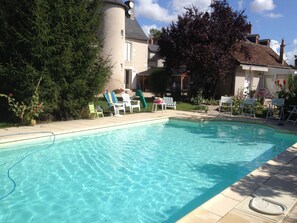 A swimming pool with clear water, surrounded by lounge chairs and a house in the background. - LA PETITE MAISON - MANOIR LE BOUT DU PONT (Huisseau-sur-Cosson)