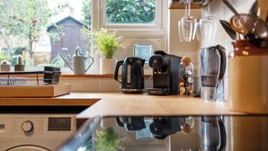 Una cucina con lavatrice, macchina del caffè e una finestra vista verde.