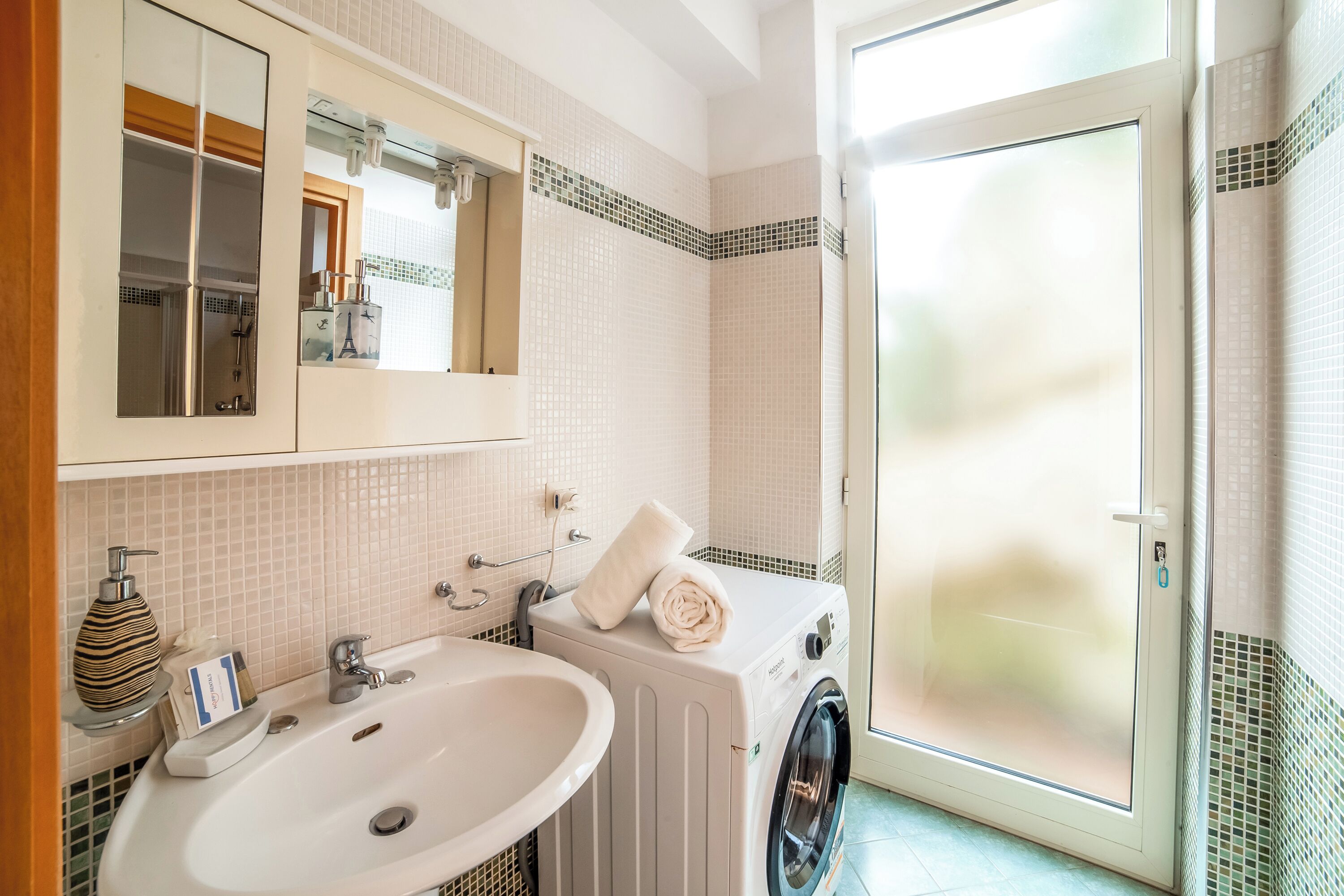 Une salle de bain équipée d’un lavabo, d’un miroir, d’une serviette et d’un lave-linge.