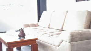 Ein beiges Sofa mit zwei Kissen, einem Holztisch und einer kleinen Vase.
