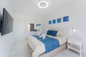 Ein modernes Schlafzimmer mit einem großen Bett, einem Nachttisch, einem Flachbildfernseher und Kunstwerken an der Wand.
