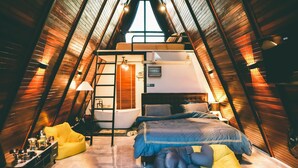 Acogedor dormitorio en el ático con una cama litera, un escritorio y un sillón de mimbre amarillo.