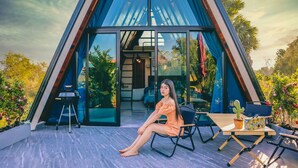 Un edificio moderno de forma triangular con grandes ventanales y un patio con mobiliario exterior.