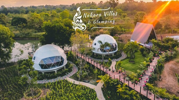 Dos estructuras de domos geodésicos rodeados de exuberantes jardines y un panel solar.