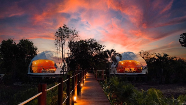 A pathway leading to two dome-shaped structures with a sunset sky in the background.