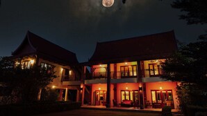 A two-story building with a balcony and a moon in the sky.