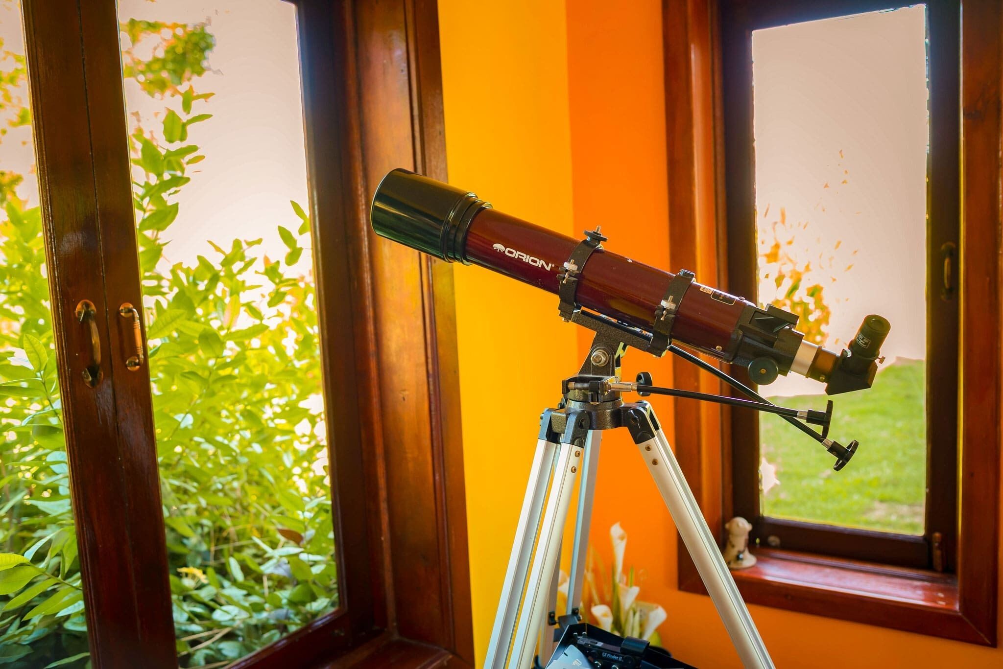 Un telescopio sobre un trípode dentro de una habitación con ventana.