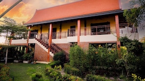 A two-story building with a red-tiled roof, a balcony on the upper floor, and a staircase leading to the upper level.