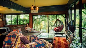 A cozy living room with a sofa, a hanging chair, and a glass coffee table.