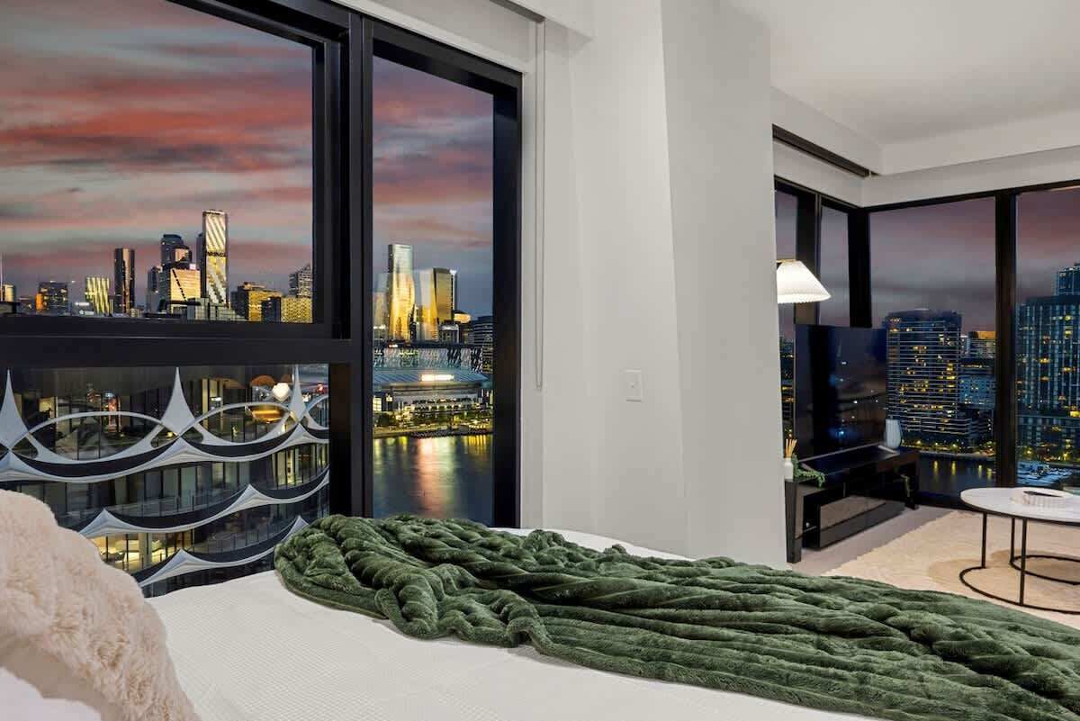 A modern hotel room with a large window offering a city skyline view.