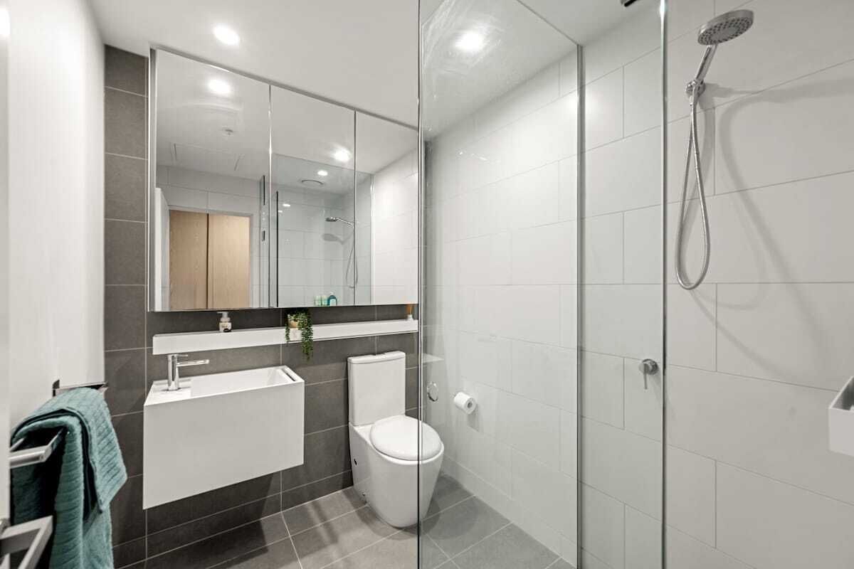 A modern bathroom with a glass-enclosed shower, a white sink, and a toilet.