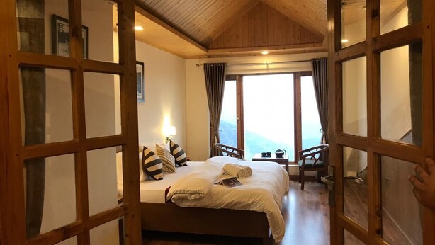 Ein Schlafzimmer mit einem großen Bett, Holzboden und Blick durch eine offene Tür.
