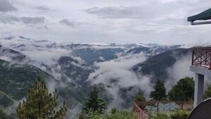Eine gebirgige Landschaft mit einem bewaldeten Tal und einer roten Metallkonstruktion.