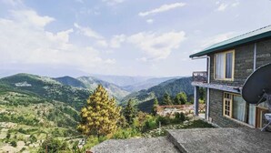 Ein Steinhaus mit einem Balkon mit Blick auf eine gebirgige Landschaft.