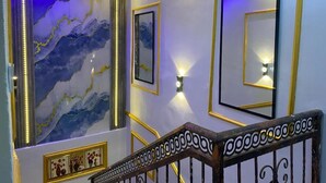 A staircase with a marble wall, framed artwork, and wall-mounted lighting. - Lakefront 2-BR-Apt With 24Hrs Power + Starlink Wi-Fi (Lagos)