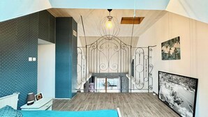 A modern bedroom with a large bed, a fireplace, and a view of the street. - Atypical enitre house with character, large volumes, tastefully decorated (Bourdons-sur-Rognon)