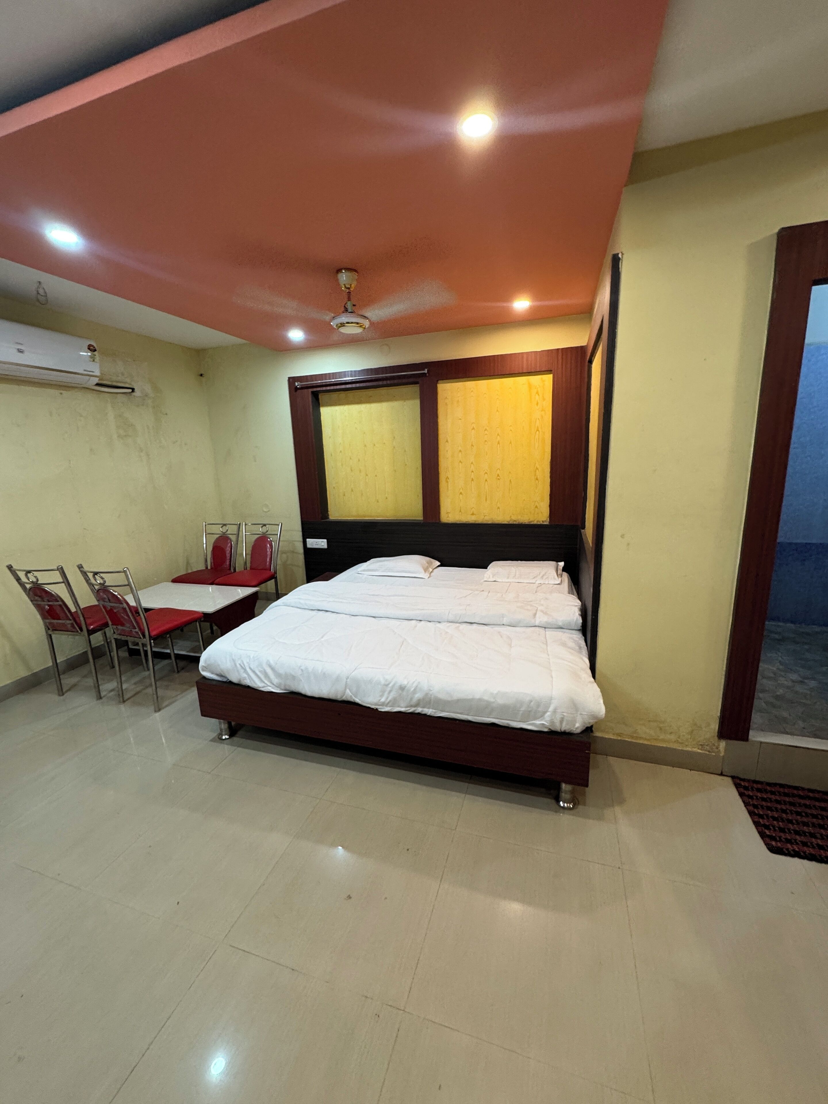 A hotel room with a bed, a table with chairs, and a window.