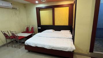 A hotel room with a bed, a table with chairs, and a window.