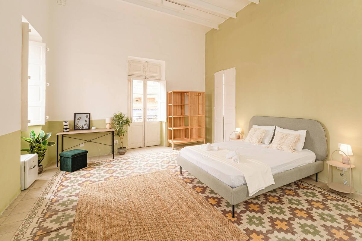 A bedroom with a bed, bedside table, lamp, and a window.