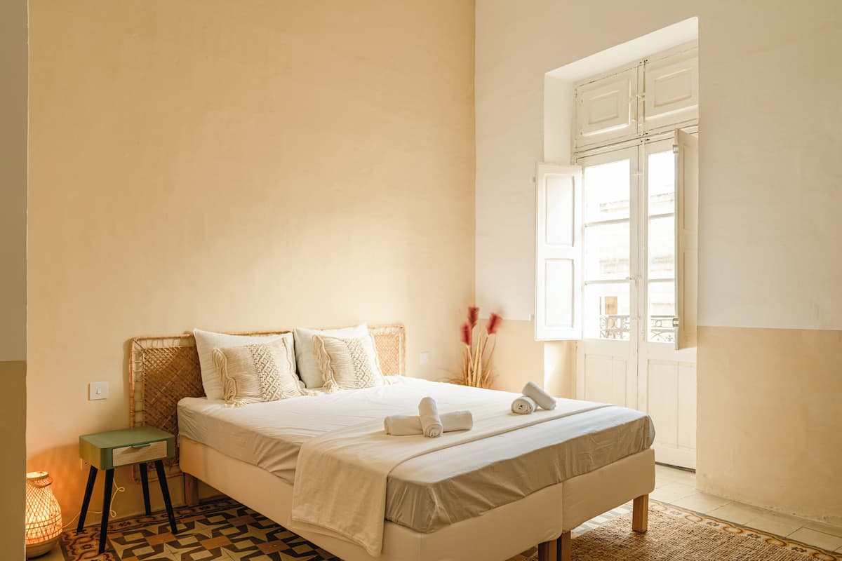 A bedroom with a bed, bedside table, and a window with a view.