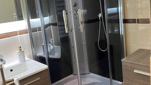A modern bathroom with a glass-enclosed shower, a white sink, and wooden cabinetry. - Le corbier Fully renovated 4-5 person apartment, at the foot of the slopes, view. (Villarembert)