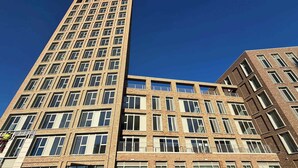 Een meerlaags gebouw met een modern architectonisch ontwerp, met een combinatie van bakstenen en glazen gevels, grote ramen en balkons.