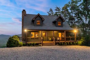 A two-story log cabin with a porch, large windows, and a chimney. - Dog-friendly Retreat with Outdoor Sauna & Hot Tub. Golf and hiking trails nearby (Blue Ridge)