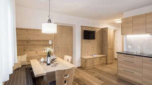 Eine moderne Küche mit Holzausstattung, einem Essbereich mit einer Bank und einem an der Wand befestigten Fernseher.