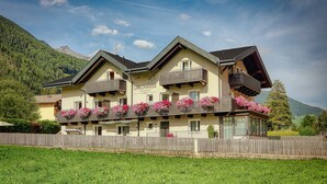 Ein mehrstöckiges Hotel mit Balkonen, die mit Blumen geschmückt sind, vor einer Bergkulisse.