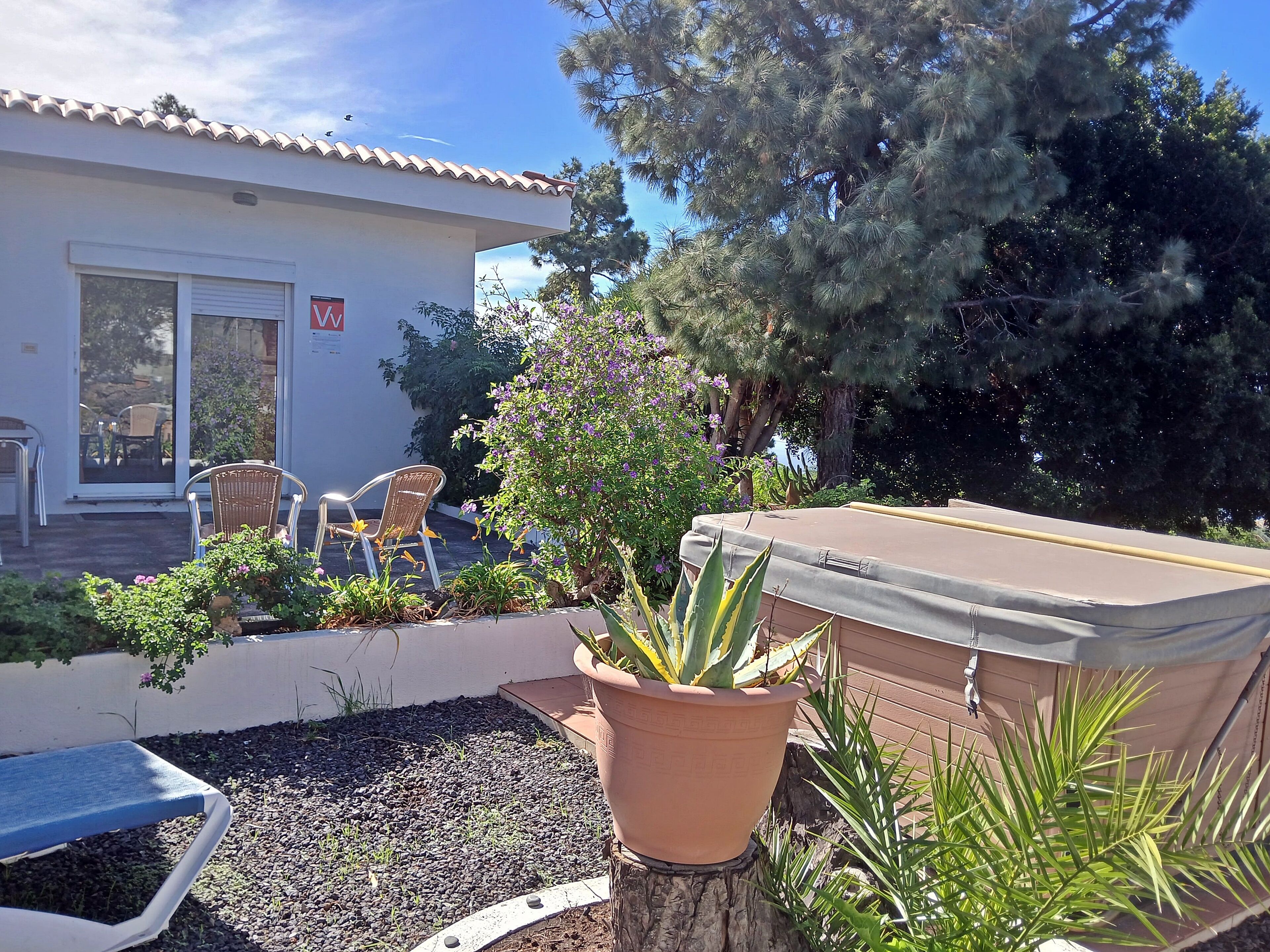 Eine Terrasse mit Grill, Blumentöpfen und Gartenmöbeln.