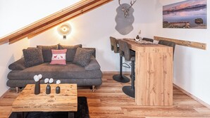 Een gezellige loft met een zithoek, een salontafel en een eethoek met stoelen en een houten tafel.