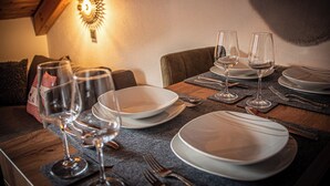 Een eettafel gedekt met borden, glazen en bestek, met een wandlamp erboven.