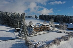 A snow-covered lodge with multiple buildings, a ski slope, and a forested area. - Cozy vacation apartment in an Alpine chalet style with a view of the mountains (Seeg)