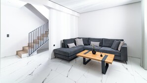 Un salon moderne avec un canapé d’angle gris, une table basse en bois et un escalier doté d’une rampe en métal.