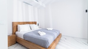 Une chambre d’hôtel moderne avec un lit en bois, du linge de lit blanc et un sol en marbre.